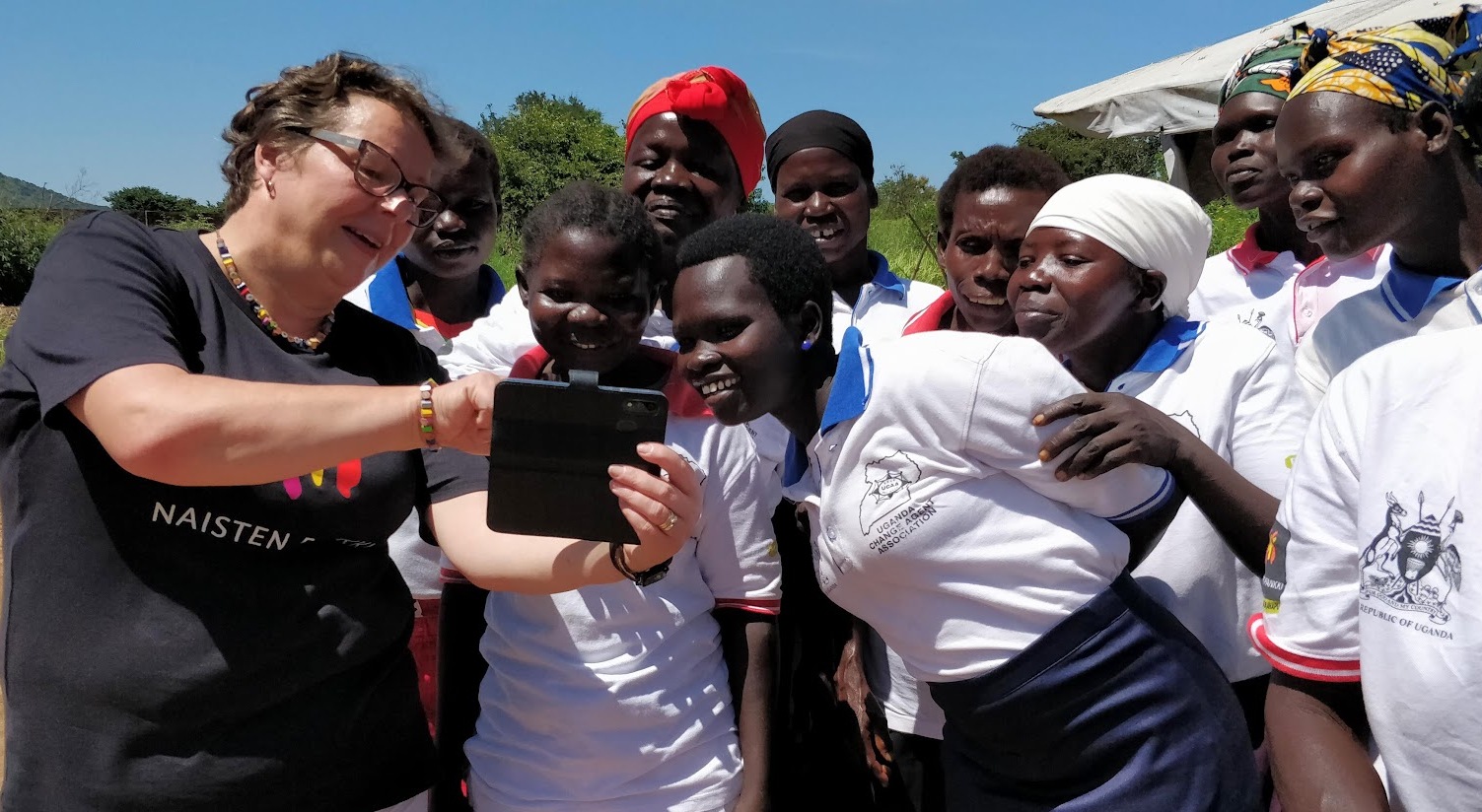 Lähetyssihteeri esittelee puhelimen näytöltä jotakin ugandalaisille naisille