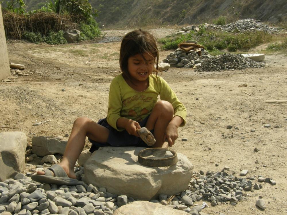 Tyttö lyö vasaralla jotakin esinettä kiveä vasten